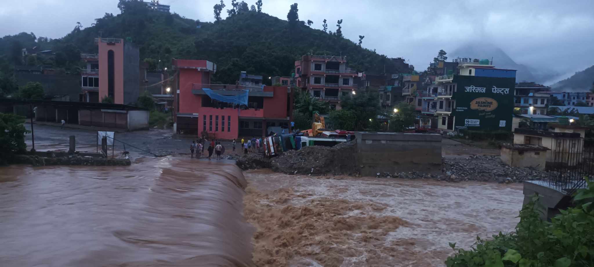 बसपार्कमा पार्किङ गरिरहेका दुईवटा बसलाई बुल्दि खाेलाले पल्टायाे
